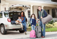 Family with two children (3 and 9 years) going on vacation, loading luggage into car.  Main focus on girl and father.